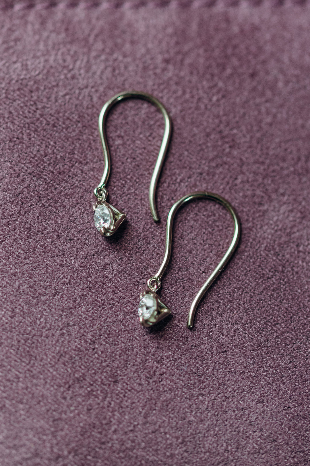 Elegante Emilia Diamantohrhänger mit zarten Haken und beweglichen Diamanten, fotografiert auf violettem Samt.