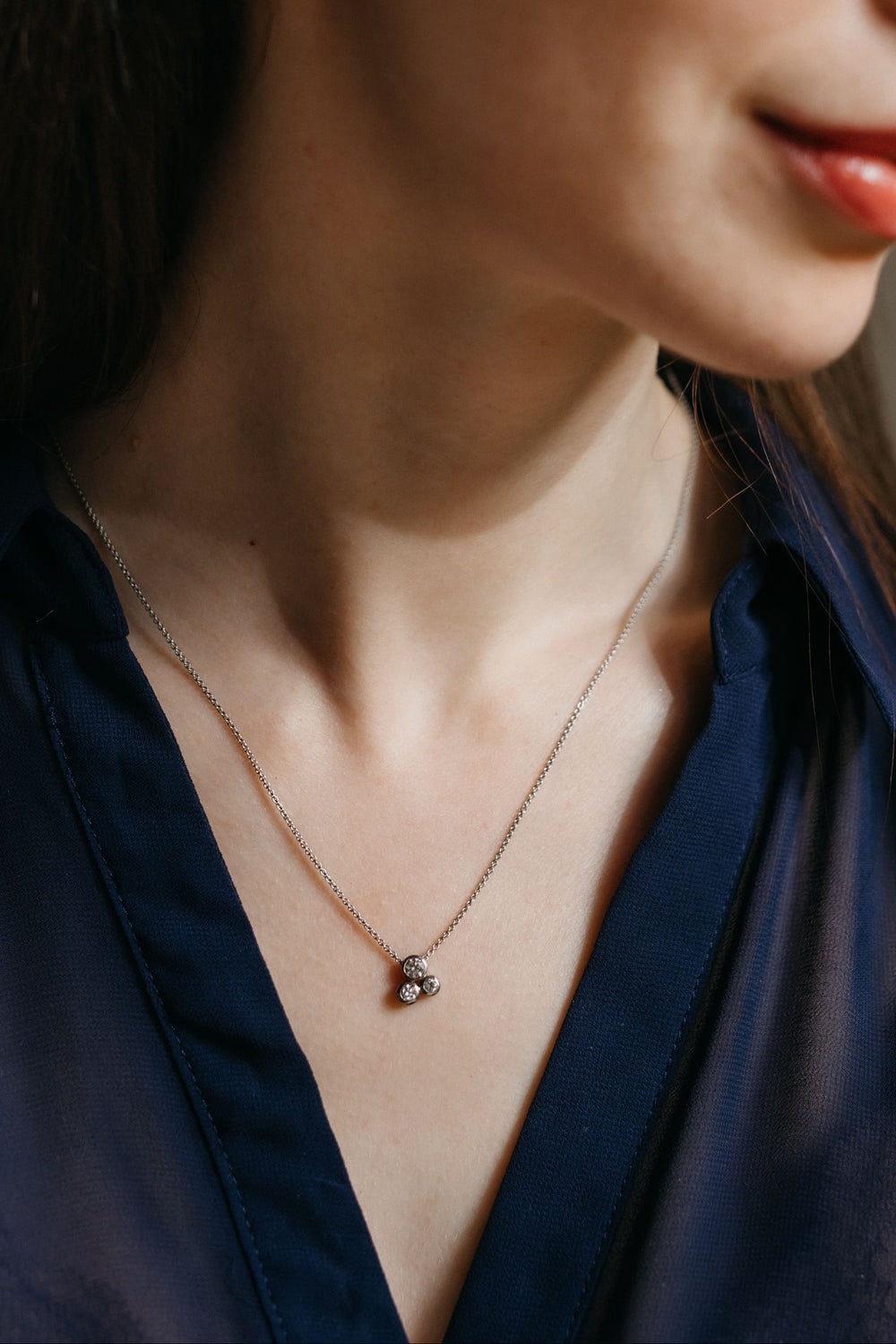 Modell trägt den Gloria Anhänger und die passenden Ohrringe in Weißgold, fotografiert im warmen Tageslicht.