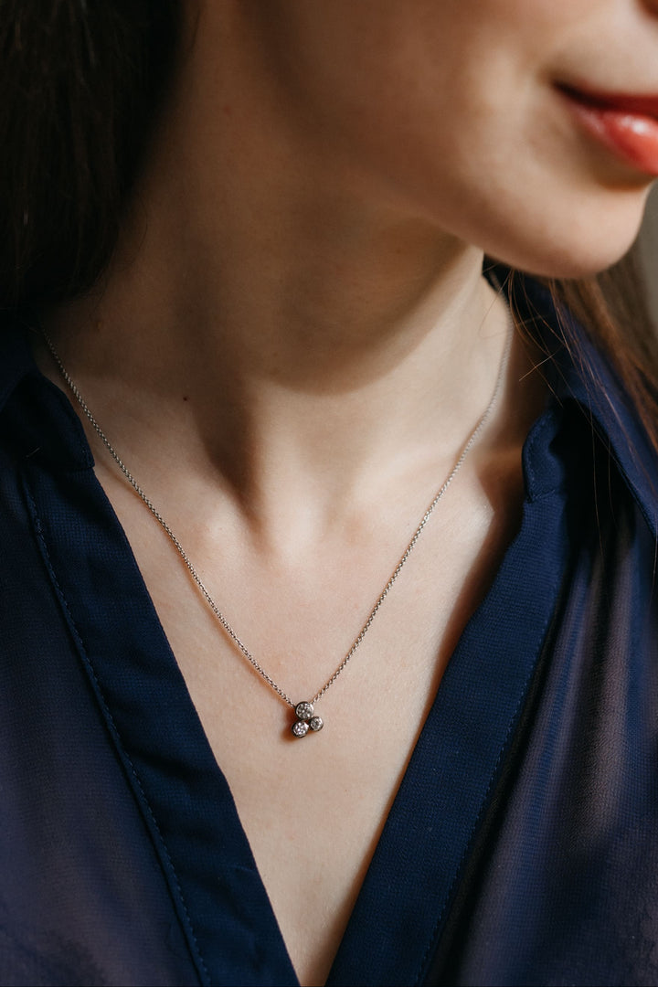 Modell trägt den Gloria Anhänger und die passenden Ohrringe in Weißgold, fotografiert im warmen Tageslicht.