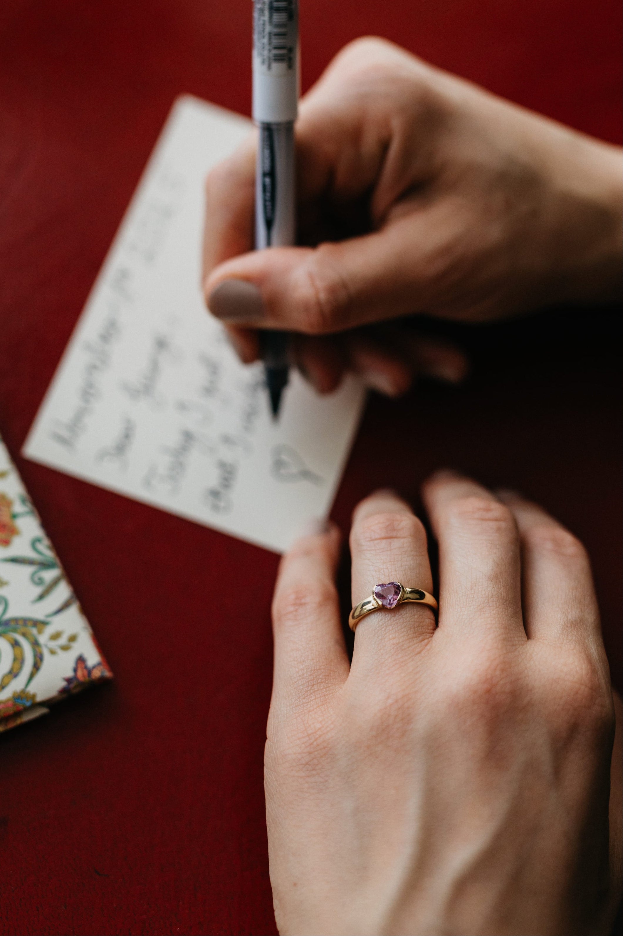 Detailaufnahme des Mon Cœur Rings aus Gelbgold mit herzförmigem Edelstein während einer Schreibszene.