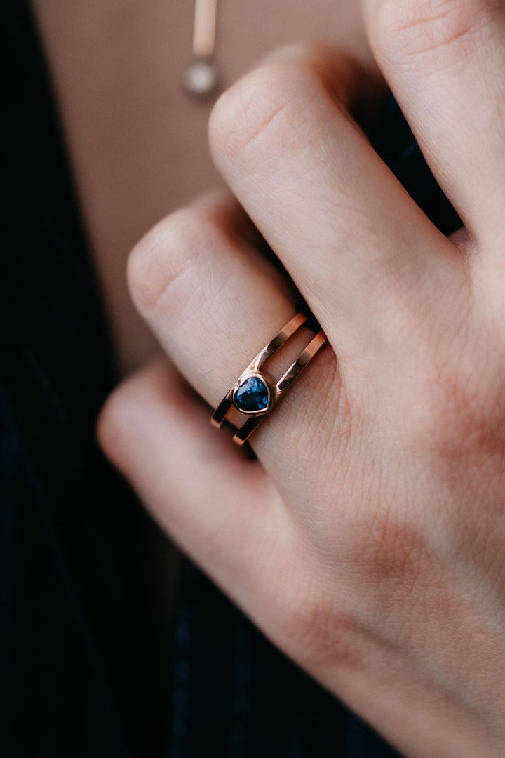 Handdetail mit dem Mon Coeur Ring aus Gold und blauem Saphir, elegant getragen vor dunklem Stoff