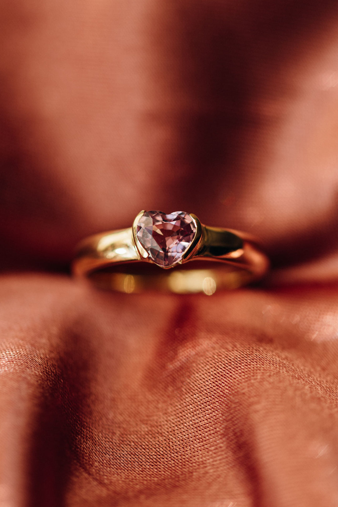 Goldring Mon Cœur mit rosafarbenem Spinell auf seidigem Stoff in Rosétönen