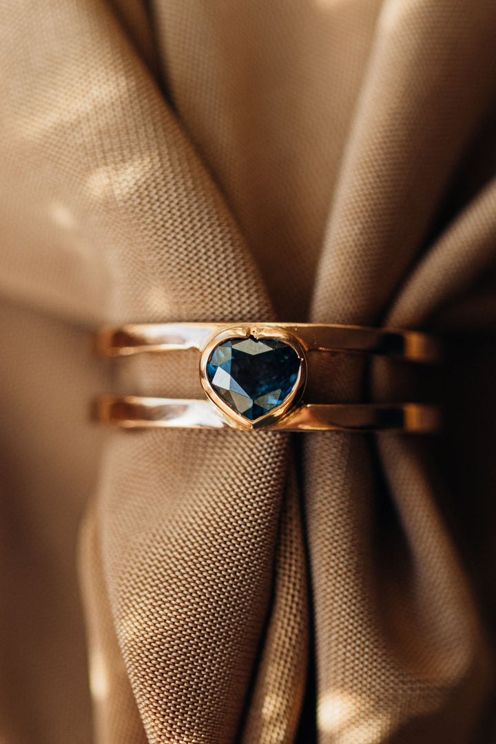Mon Cœur Ring mit herzförmigem blauem Spinell auf edlem goldbraunem Stoff