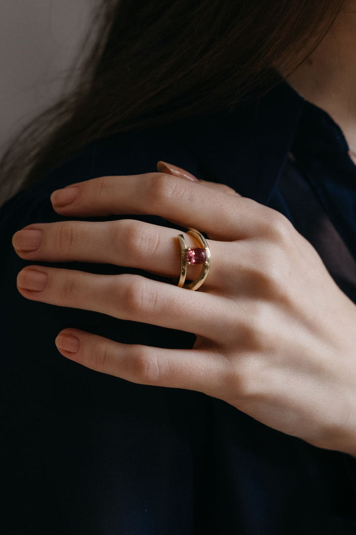 „Hand mit dem Mon Petit Chou Ring aus Gold mit pinkem Turmalin, elegant über die Schulter gelegt.