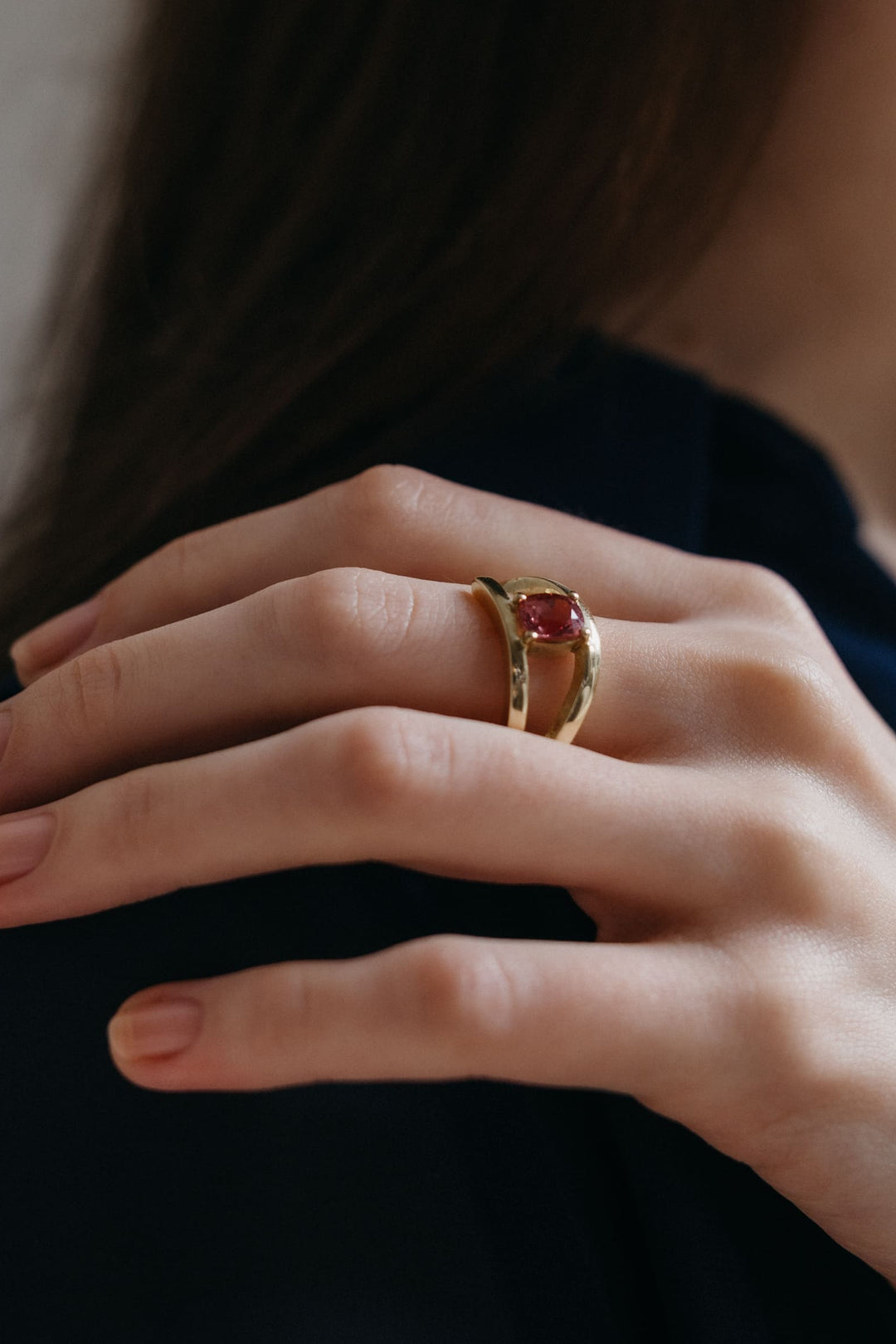 Nahaufnahme des Mon Petit Chou Rings aus Gold mit pinkem Turmalin, getragen an der Hand, seitliches Portrait.