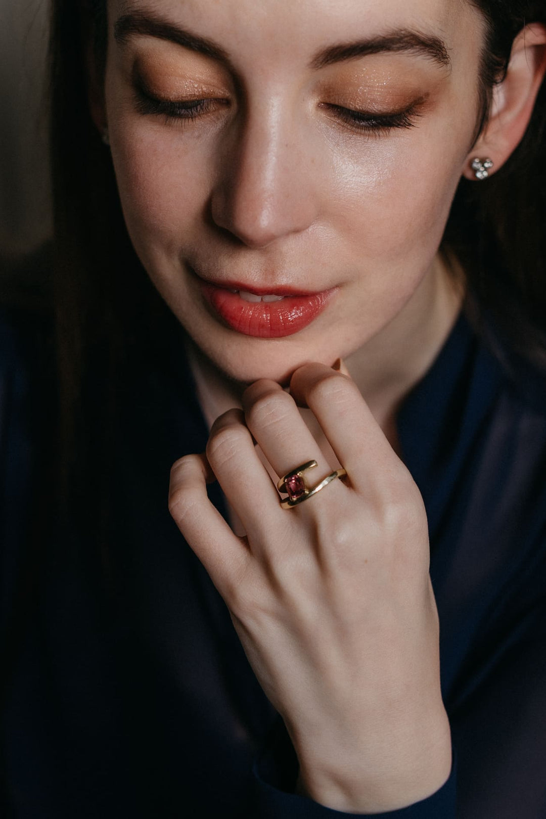 Portrait einer Frau mit dem Mon Petit Chou Ring aus Gold mit pinkem Turmalin, Fokus auf Hand und Gesichtsausdruck.