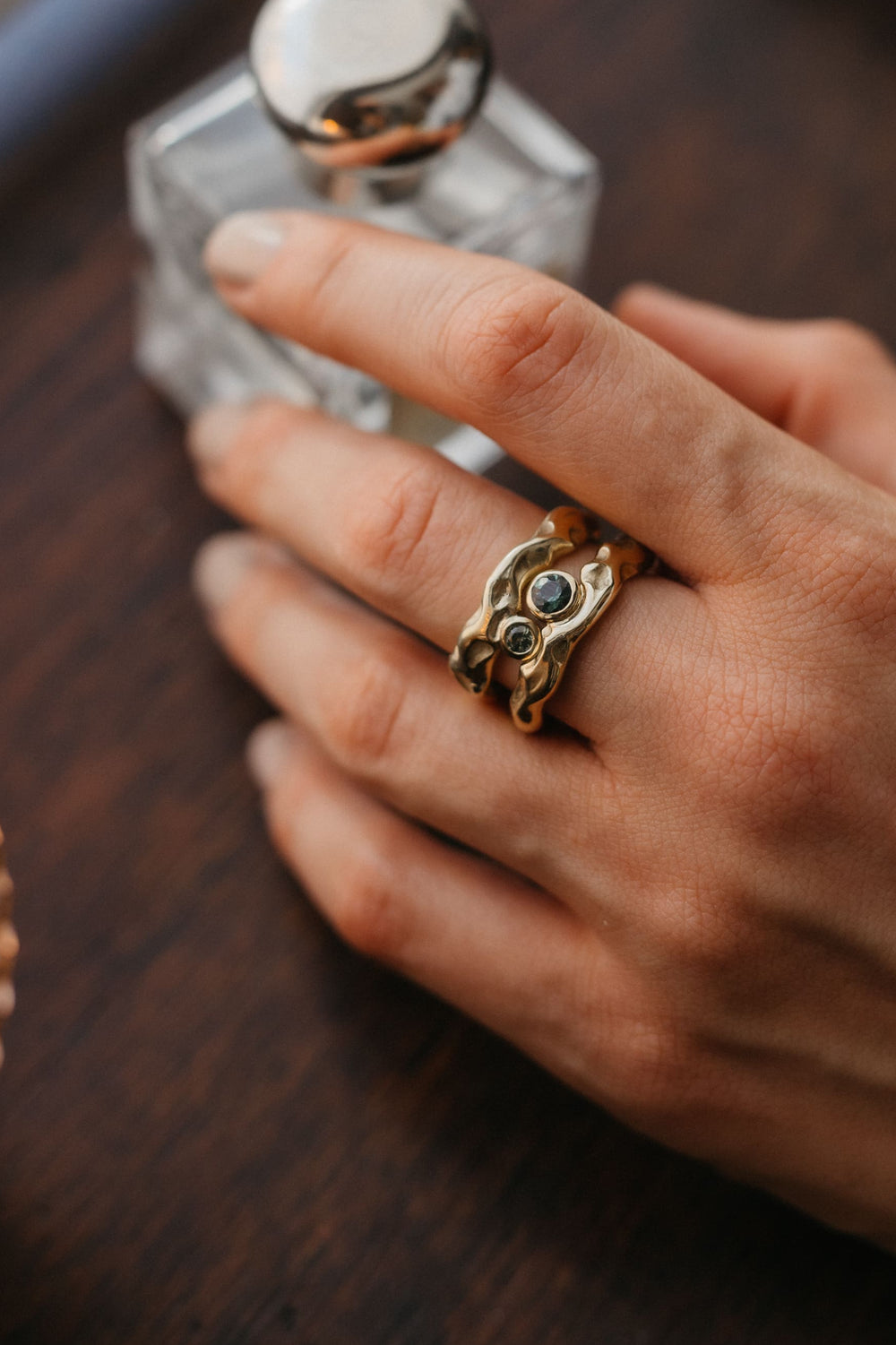 Mystery Ring aus Gold mit blauem Edelstein, fotografiert in warmem Kerzenlicht