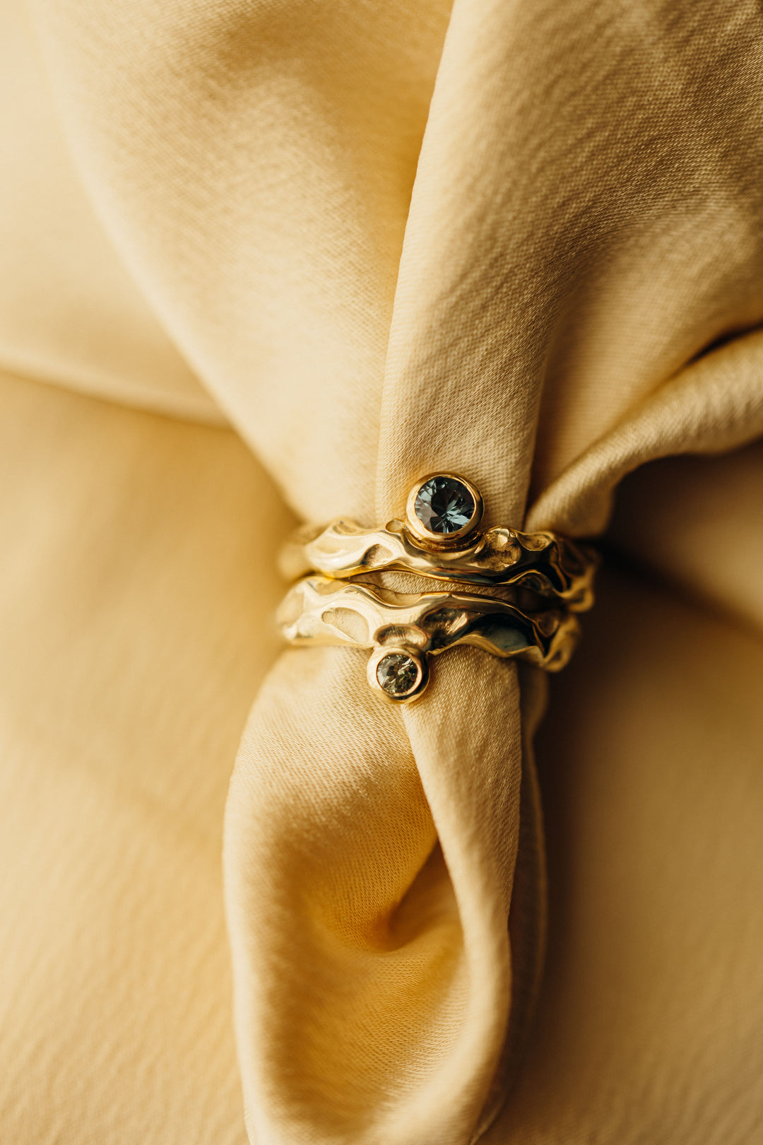 Handgefertigter Mystery Single Ring aus Gold mit natürlicher Wellenform und Turmalin, dekorativ auf weichem Stoff arrangiert.
