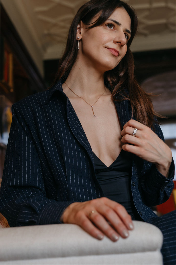 Person, die Valentina-Halskette und Valentina-Ohrringe trägt, sitzend in einem kunstvollen Wohnzimmer.