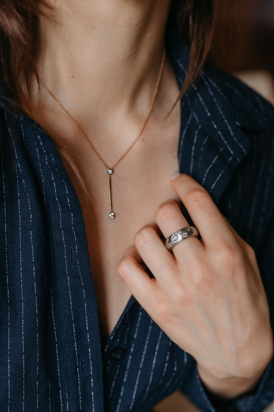 Valentina-Halskette und diamantbesetzter Ring im Styling an der Hand und am Hals einer Person.