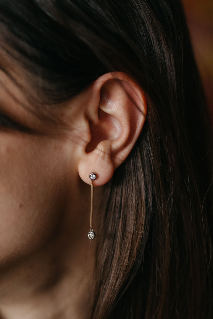 Nahaufnahme eines Valentina-Ohrrings aus Gelbgold mit zwei Diamanten am Ohr einer Person.